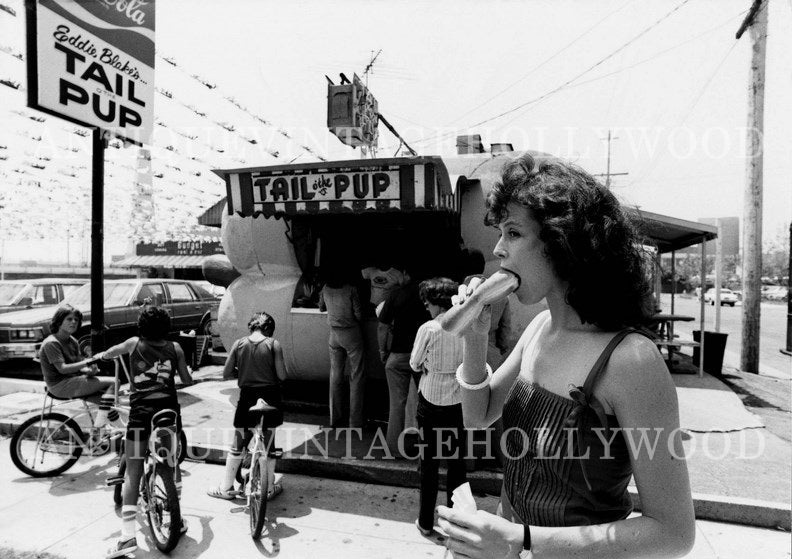 Young actress Sigourney Weaver eats a hot dog at the iconic Tail O' the Pup diner in Los Angeles in 1983. А00028