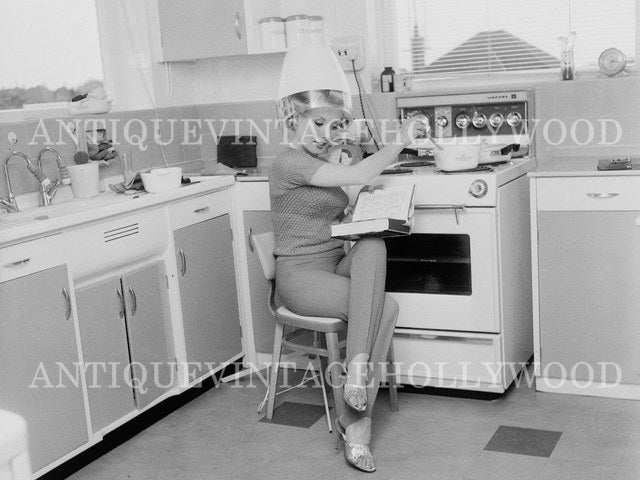 British actress Barbara Roscoe reads and cooks, all while using a hairdryer at her home. A00059