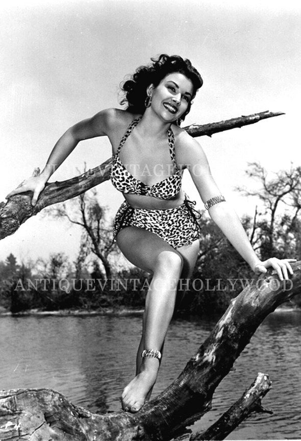Mara Korday, an American actress and model of the 1950s, posing on a tree branch in a leopard-print swimsuit. А00085