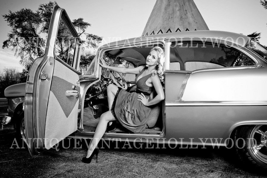 A woman in retro style sitting in the doorway of a classic American car. А00089